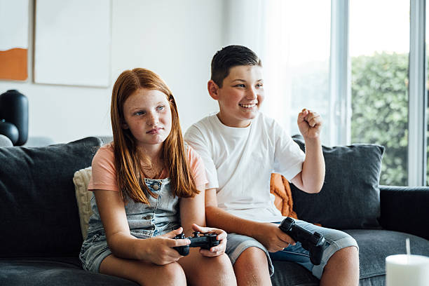 Two children, a boy and a girl playing video games at home
