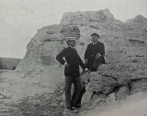 Antique illustration pre 1900 - two men sitting on a rock formation near The Castle Geyser's Cone - Yellowstone National Park