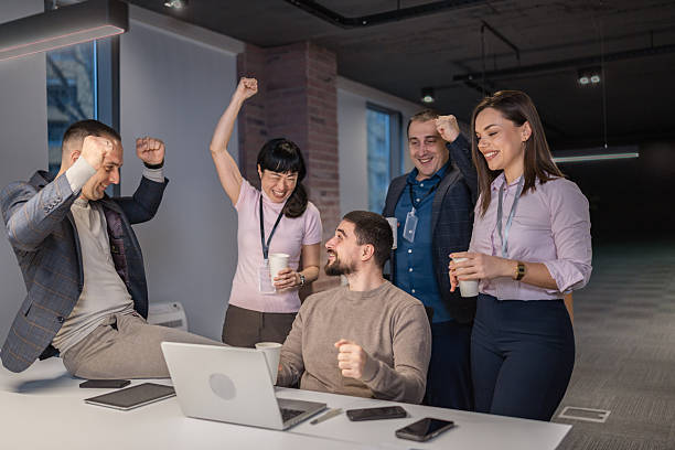 istock Happy office colleagues celebrating success around a laptop. 2254909673