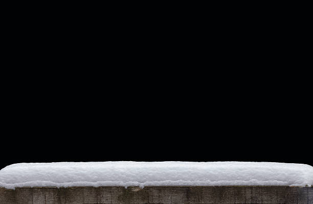A snow hat on a rustic wooden table against a black background.