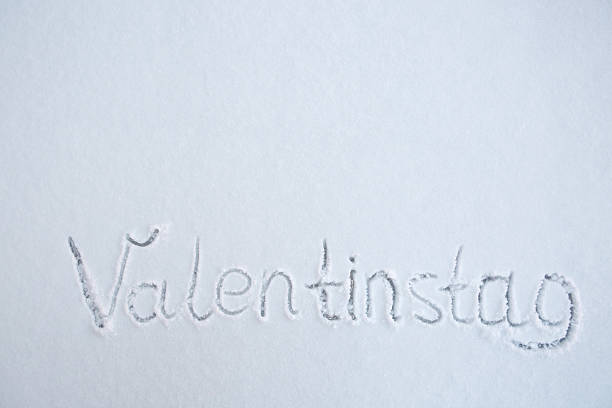 Inscription Valentines Day written on white snow.