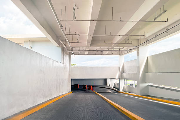 Underground multi-level parking garage ramp with ascent and descent lanes, modern concrete architecture and empty vehicle access road