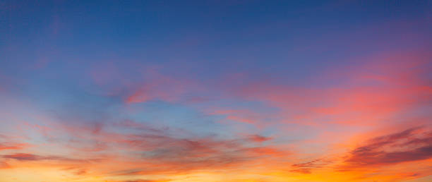 istock Vibrant Panoramic Sunset Sky with Dramatic Pink and Orange Clouds,A breathtaking panoramic view of a sunset sky featuring a vivid transition from deep blue to brilliant orange and pink hues, with soft wispy clouds scattered across the horizon. 2254918599