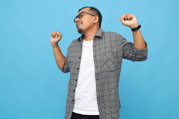 istock Asian man yawning, stretching, raising hands, isolated on blue background 2254925690
