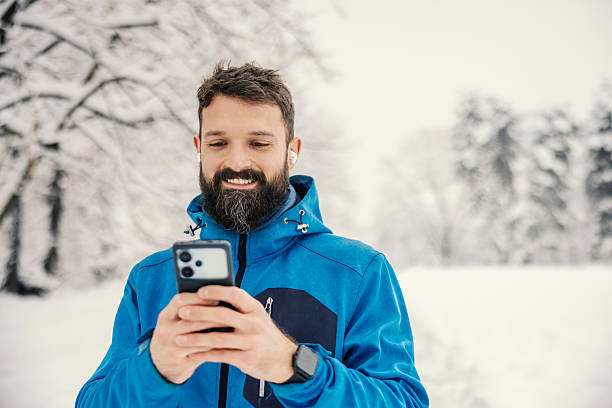 istock Smiling man using smartphone browsing outdoor in winter 2254926861