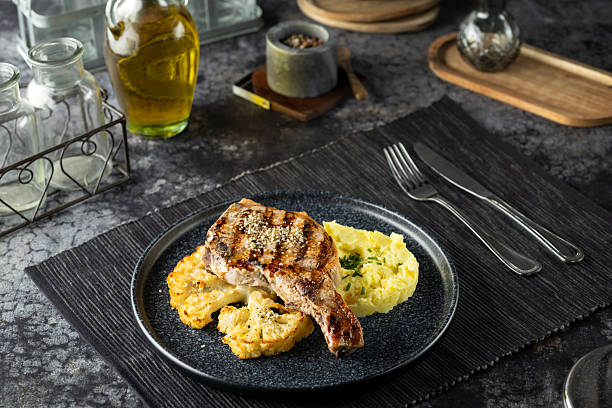 Delicious plated dinner featuring a gourmet grilled pork chop with creamy mashed potatoes and roasted cauliflower