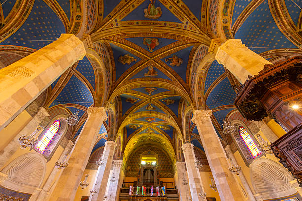 Intricate vaulted ceiling and columns depicting religious art inside historic italian church