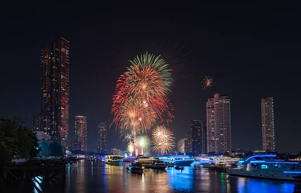Festive Skyline Festive fireworks display over a modern river skyline for Christmas and New Year events. Beautiful night scene with glowing city lights, cruise boats, and pyrotechnics over the water.