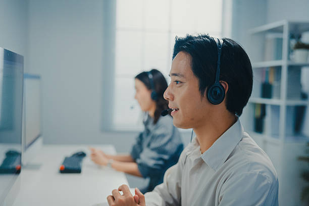istock Young Asian customer service representative wearing headset assisting client specialist helping client solving request at call center office. Professional work data center. Helpdesk operator concept. 2254933102