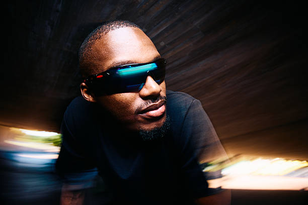 Close up of a focused young man leaning forward while resting in an urban tunnel in motion blur, taking a break from intense cardio workout and endurance training.