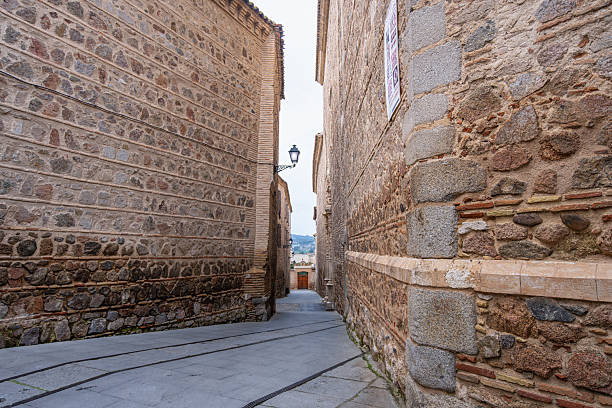 a narrow street in Segovia with medieval buildings and stone steps with metal wrought iron railings