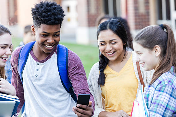 istock Teenagers sharing a laugh while looking at a smartphone together outside school. 2254935818