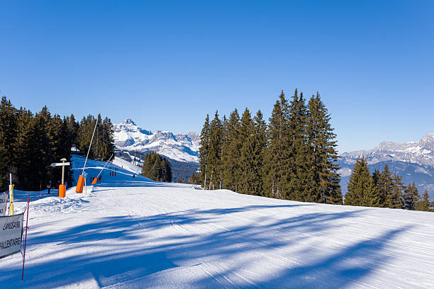 Ski lift and snowy piste with mountain panorama
