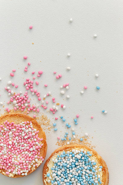 Multiple plates of traditional Dutch beschuit met muisjes pink and blue birth announcement treats with cheese wheel background for celebration