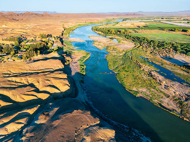 flight over orange river at namibian and south african boarder at sunset, with desert on one and green fields at the other riverside