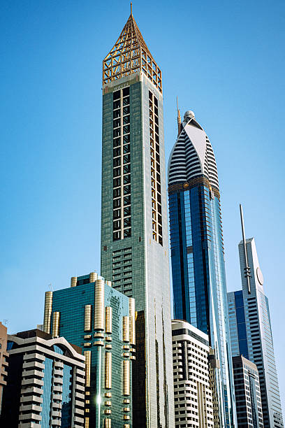 Dubai's modern skyline with towering skyscrapers and glass exteriors rises against a bright blue sky, highlighting futuristic architecture, urban growth, and luxury city life.