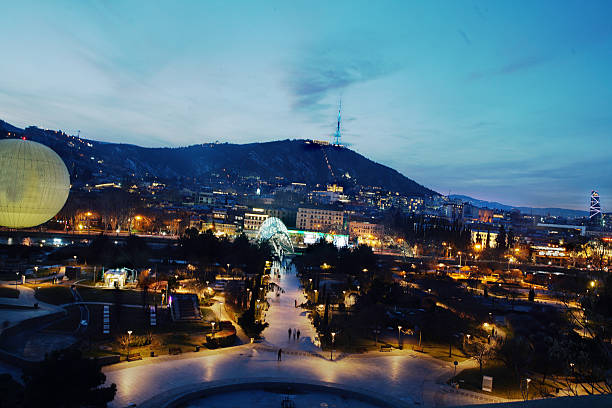 Blue hour view on Illuminated Tbilisi: Pedestrain bridge of Peace and TV tower (which change colors) an Statue Mother Georgia in distance