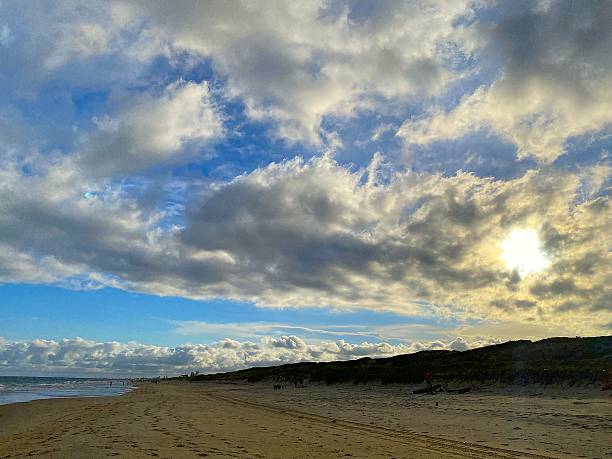 istock Sun filtered through clouds on a vast, deserted beach with dunes. 2254956296