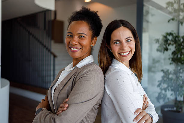 istock Diverse businesswomen smiling, collaborating and standing back to back, showcasing teamwork and partnership in a modern office 2254956856