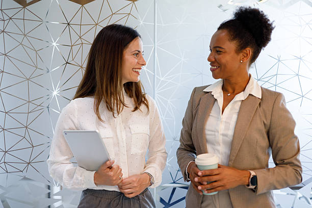 istock Diverse businesswomen smiling and interacting in office setting, discussing work during a break 2254957951