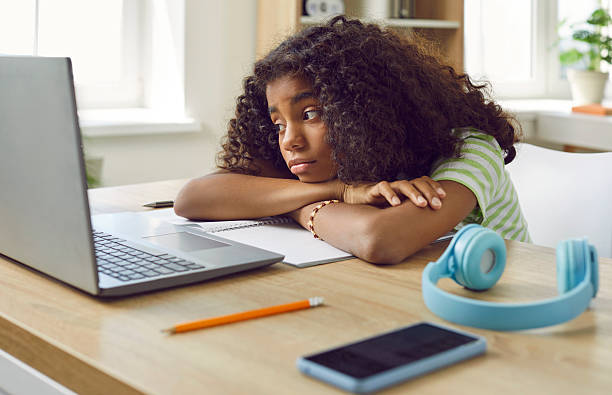 Sad, bored, tired school child thinking about something else during online class