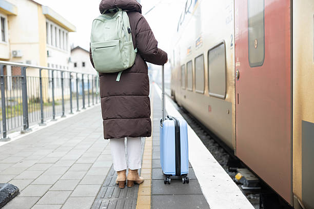 A woman walks confidently toward the train, her suitcase trailing behind as she embraces travel's excitement.