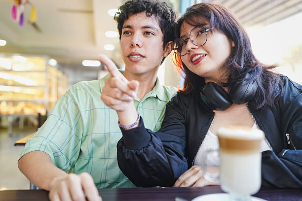 Young couple enjoying cafe time while pointing and smiling