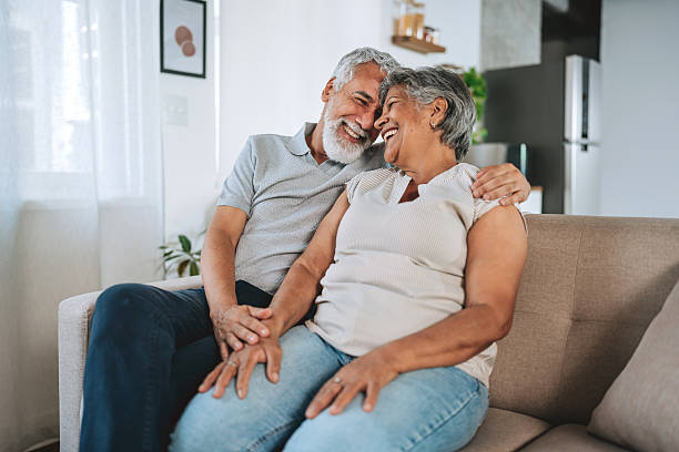 istock Happy Smiling Senior Couple Cuddling and Touching Heads on Sofa 2254960478