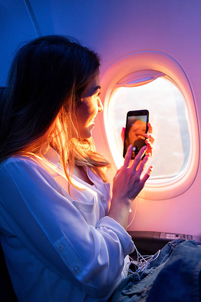 istock Young woman taking a selfie video call on a plane during a vibrant sunset. 2254961276