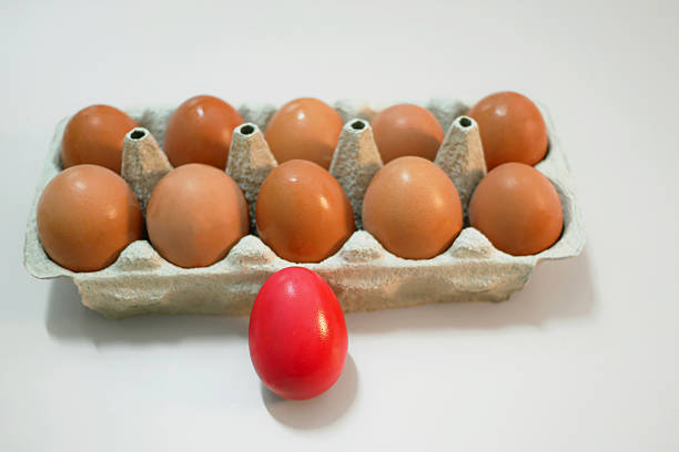 Red dyed Easter eggs placed in front of a carton of natural brown eggs. Festive spring composition for Easter, tradition, and holiday themes.