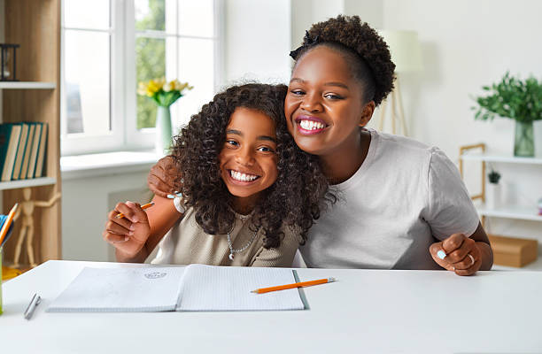 Happy African American mother and daughter having fun while doing homework together