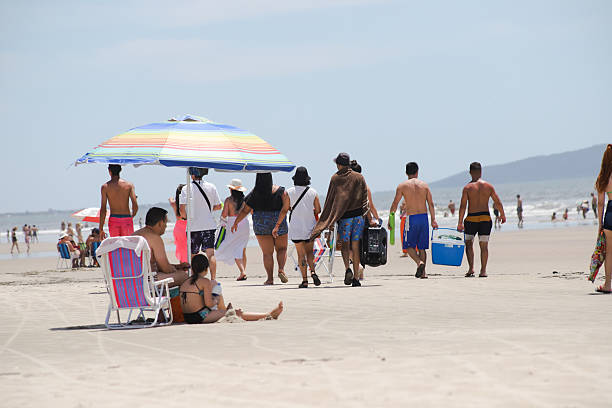Rio de Janeiro locals enjoy a leisurely walk where the ocean meets the sand at Copacabana Beach.