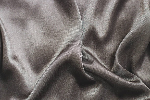 istock Smooth dark fabric lying on a flat surface with soft folds and creases 2254966253