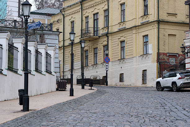 A peaceful cobblestone street curves gently past elegant yellow buildings. Andreevsky Uzviz, Kyiv, Ukraine. December 8, 2025.