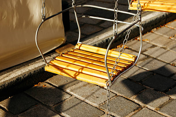 Empty playground swings on sunny day with chain leaves