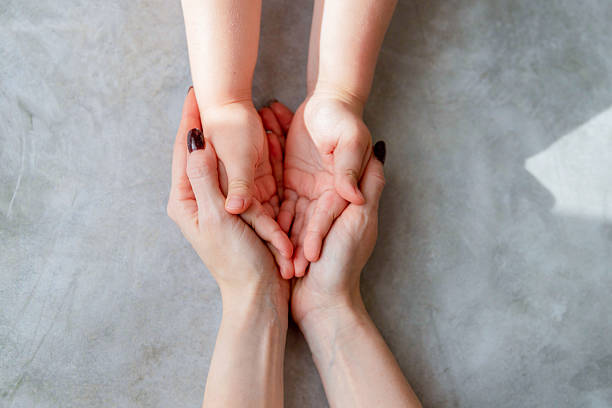 Mother and child holding hands on light blue background, closeup.