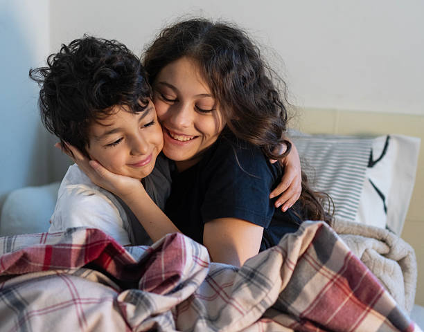 Siblings hugging and smiling together in bed