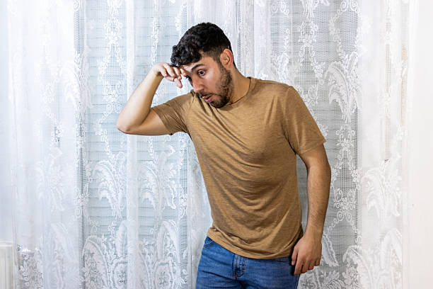Young adult man looking down with a curious and uncertain expression