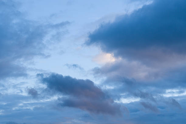 Layered blue and lavender clouds drift across a tranquil evening sky, with soft gradients and gentle light creating a calm, atmospheric scene.