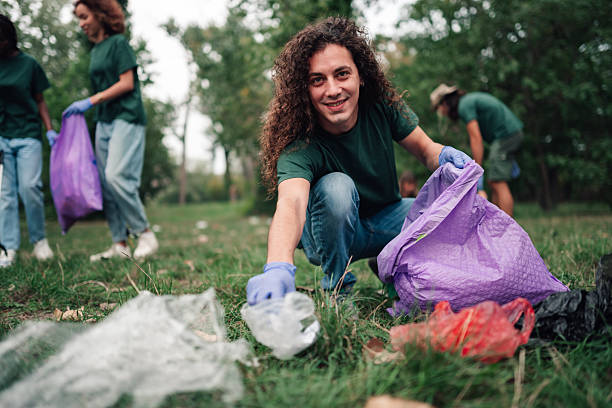 istock Young man volunteering cleaning park environment with community group 2254979530
