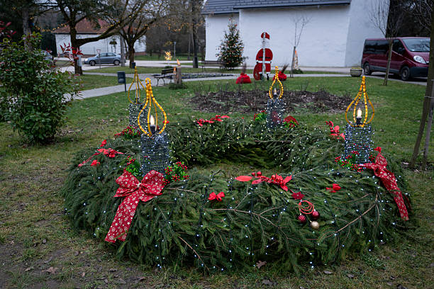 Advent wreath with evergreen boughs and red berries with three candles lit shot from tabletop with copy space