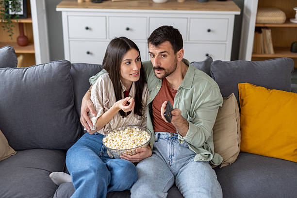 istock Loving Couple Sharing Popcorn and Glancing at Each Other 2254983973