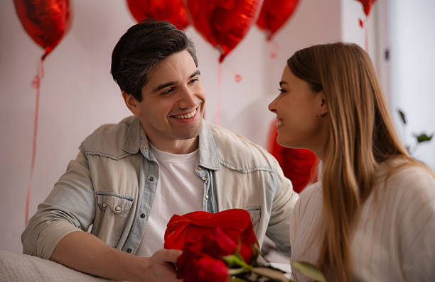 istock Happy young man surprising his girlfriend with roses and heart gift box. 2254984869