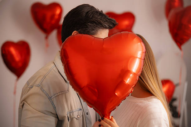 istock Couple Hiding Behind Heart Balloon 2254984948