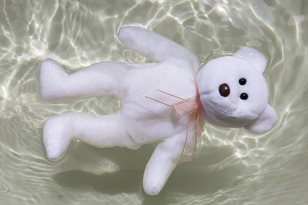 A white teddy bear floating on bright rippling water.