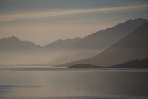 istock Lake and mountain view with subtle sunset hues 2254998220