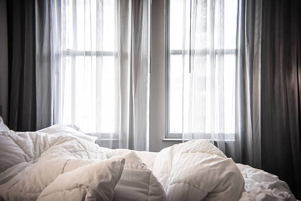 Unmade bed with natural light coming through sheer curtains in Fort Collins, Colorado, United States