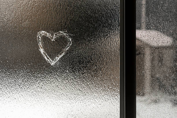 Heart etched in the ice of a window on a snowy day