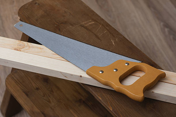 Hand saw placed on a wooden board prepared for cutting during carpentry work. Concept of construction, woodworking, repair and DIY projects