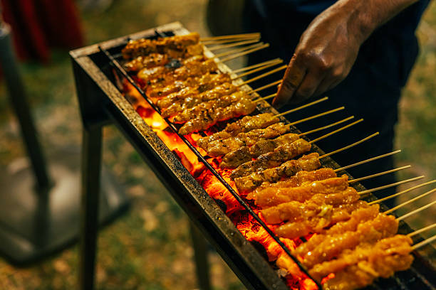 Asian night market view, chicken satays are cooking on barbecue.Penang Island - Malaysia.